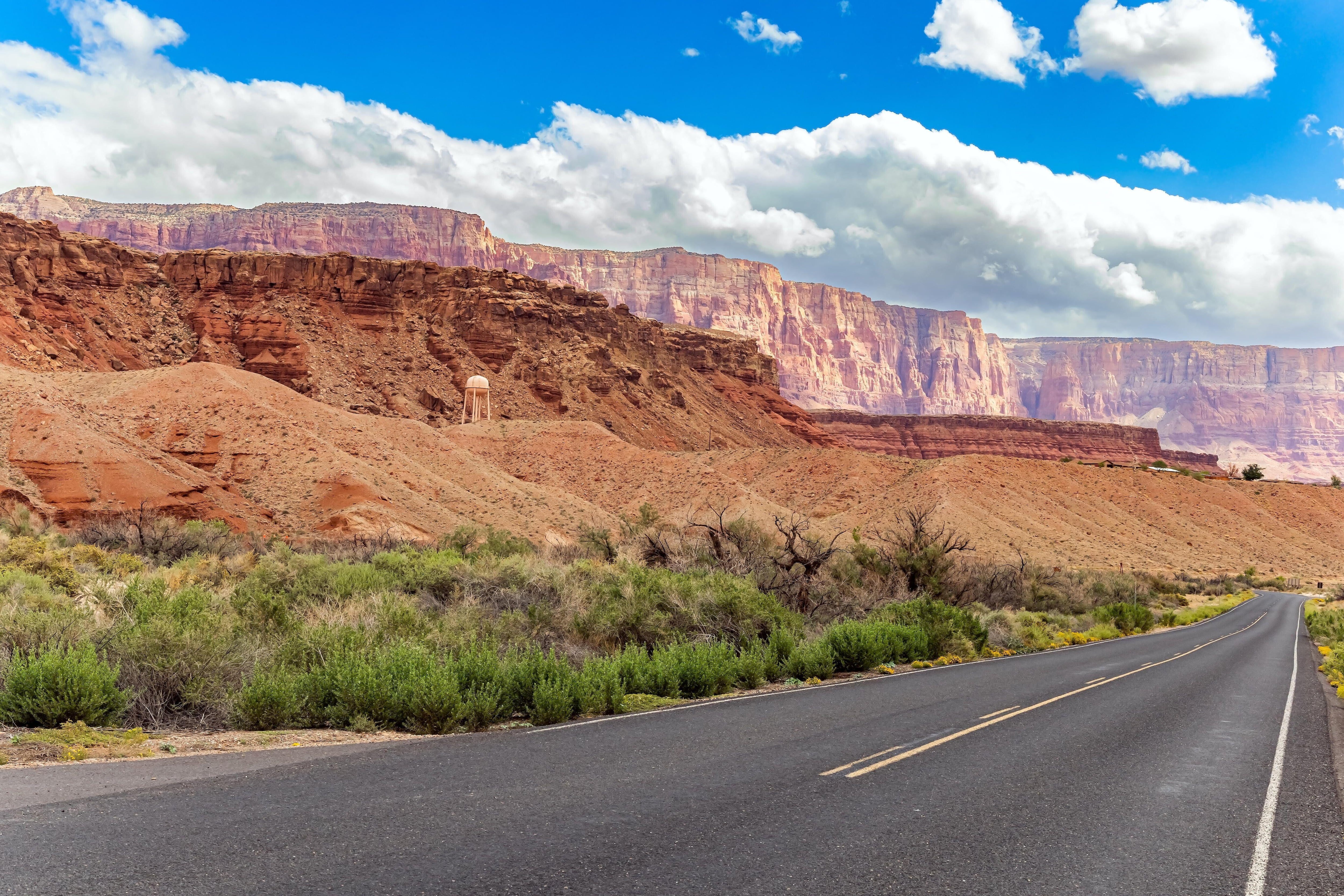 Beautiful paved highway leads to Lees Ferry crossing across the Colorado River. USA. The banks of the river are made of reddish-brown shale deposits. Cool autumn day.