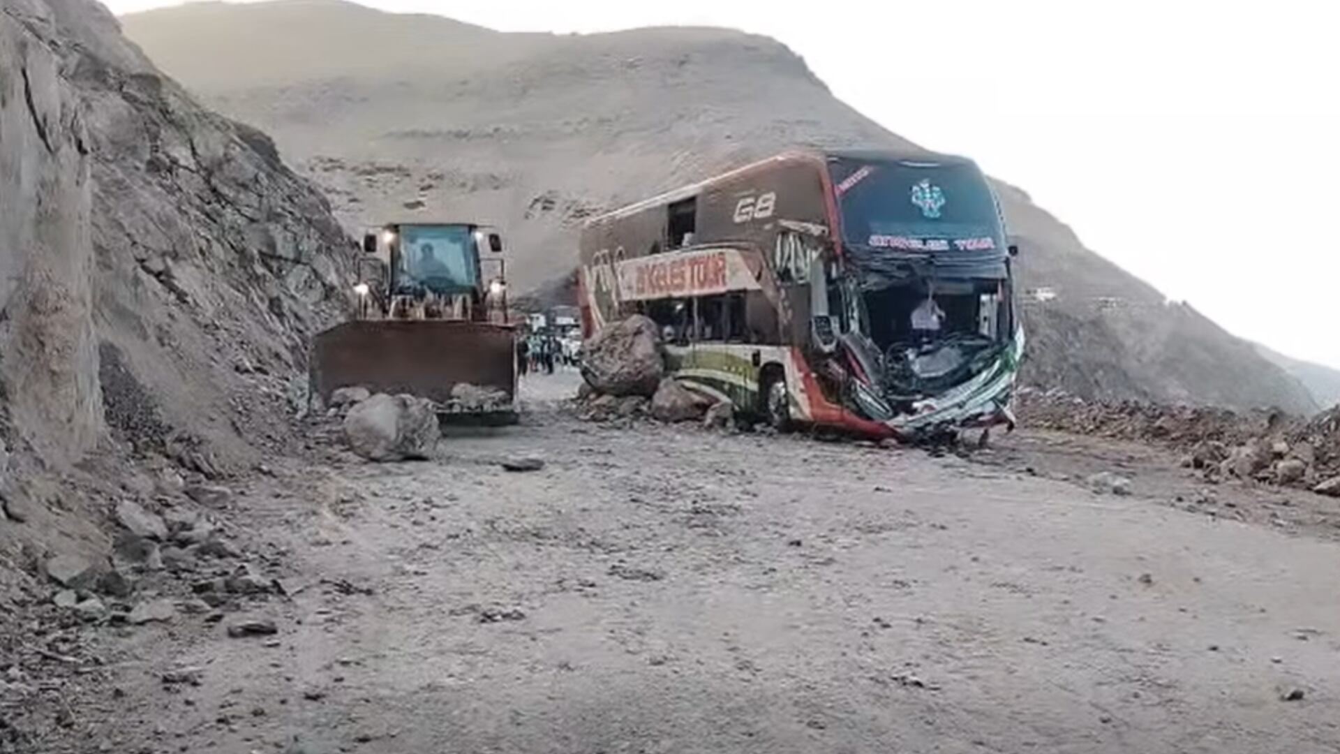 Una máquina pesada retira piedras de la carretera Panamericana Sur junto a un autobús interprovincial dañado por un derrumbe en Camaná. (Foto: Radio Ocoña Super Stereo 98.5 Fm )