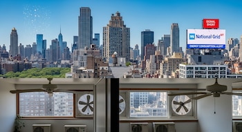 Fotografía panorámica del skyline de Nueva York bajo un cielo azul brillante con efecto de calor. Rascacielos con muchos aires acondicionados, ventiladores y un cartel de National Grid NY.