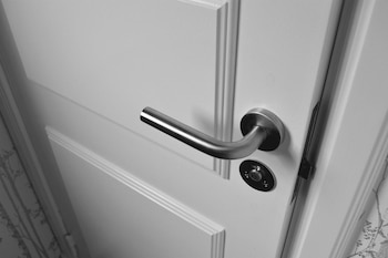Puerta blanca con panel. Picaporte metálico plateado. Cerradura con botón de seguridad