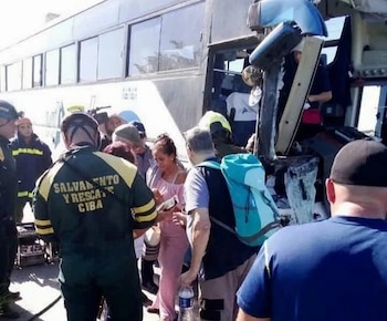 Personal de emergencia de salvamento atiende a personas al lado de un autobús con daños en su parte delantera
