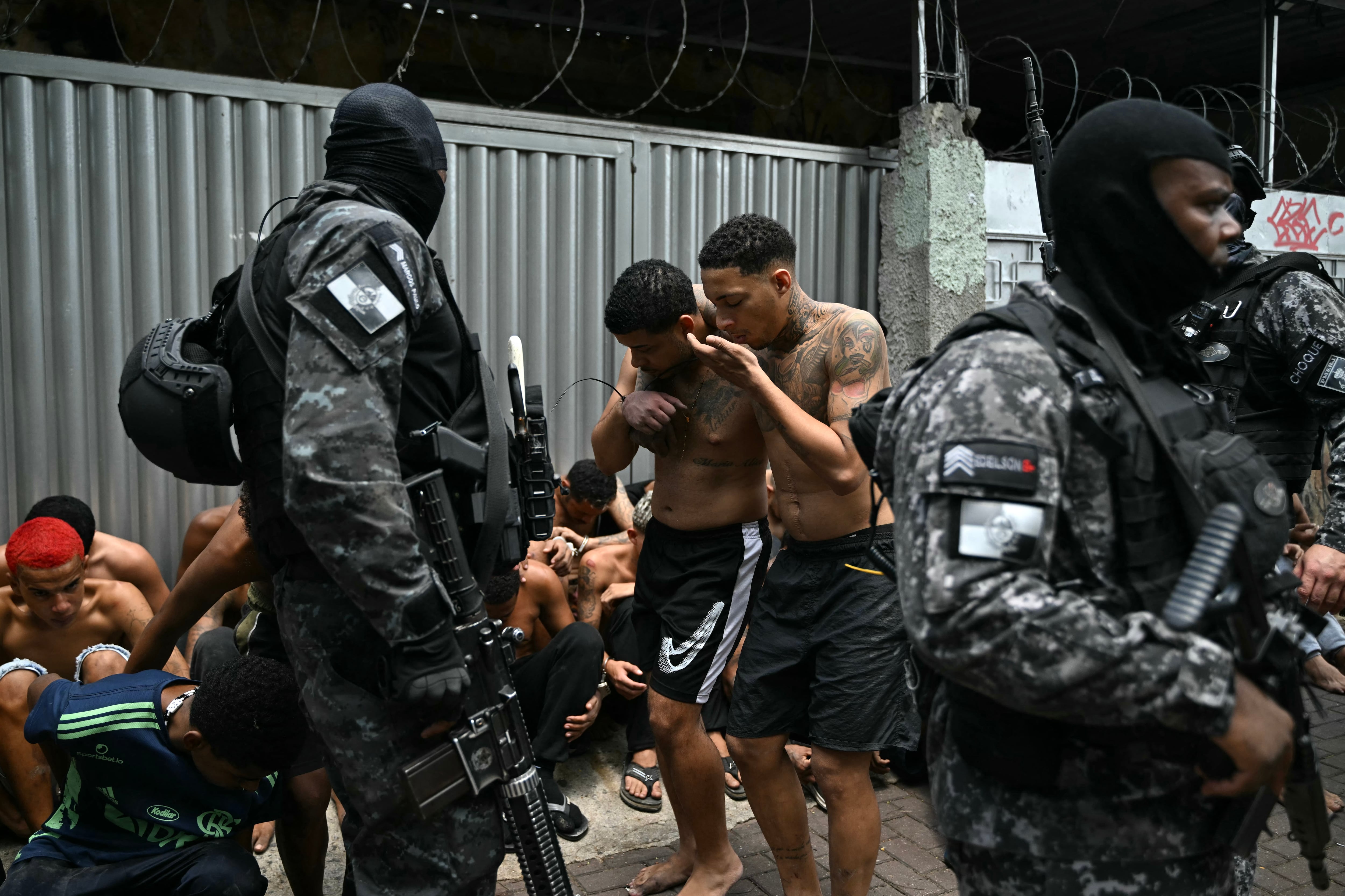 Agentes de seguridad permanecen junto a presuntos integrantes del Comando Vermelho arrestados en un megaoperativo en el complejo Penha de Río de Janeiro (AFP/Archivo)
