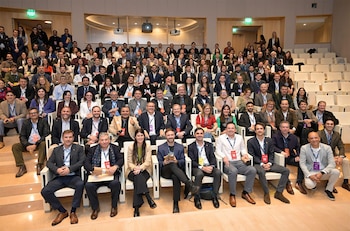 Amplio grupo de profesionales de diversas edades y géneros posando para una foto en un auditorio, algunos sentados y otros en primera fila