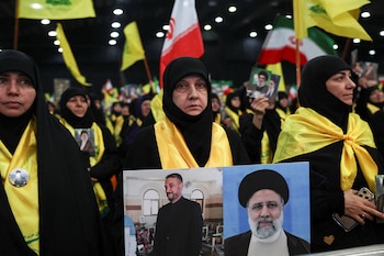 Una mujer en Beirut exhibe fotos del presidente de Irán, Ebrahim Raisi, y el ministro de Asuntos Exteriores iraní, Hossein Amirabdollahian (REUTERS/Emilie Madi)