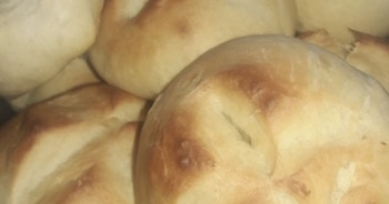 Primer plano de varios panes redondos y horneados, con una superficie dorada y suavemente tostada, apilados uno sobre otro