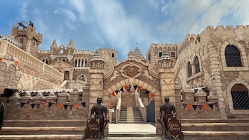 Entrada de piedra del Castillo de Chancay con dos figuras de armaduras medievales, un arco central, escaleras y banderines