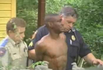 Dos agentes de policía sujetan a un hombre con el torso descubierto y las manos esposadas a la espalda en un entorno exterior