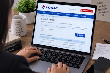 Manos sobre el teclado de una computadora portátil que exhibe la página de consulta RUC del portal de la SUNAT en un escritorio