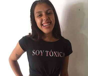 Una joven sonriente con cabello oscuro viste una camiseta negra con la frase Soy Tóxica sobre un fondo claro