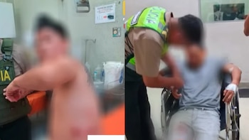 Dos hombres con el rostro difuminado, uno sin camiseta y otro en silla de ruedas, permanecen junto a policías en una sala médica