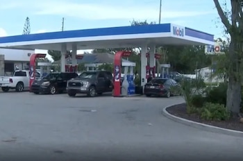 Una gasolinera de la marca Mobil con varios vehículos aparcados junto a los surtidores de combustible bajo una estructura azul