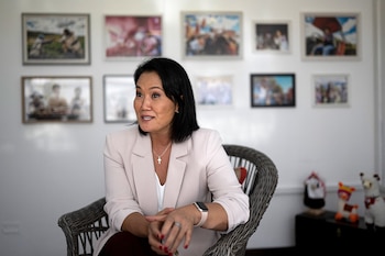 Keiko Fujimori, candidata presidencial peruana, sentada en una silla de mimbre, vistiendo un blazer claro y una cruz. En el fondo, una pared blanca con cuadros