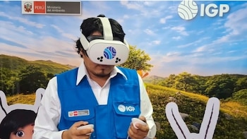 Hombre con lentes de realidad virtual blancos y chaleco azul con logo del IGP, sosteniendo controladores. De fondo, logos del Ministerio del Ambiente e IGP