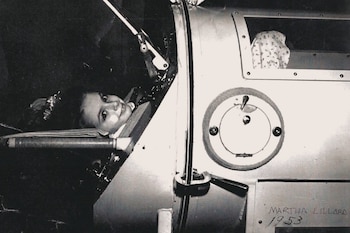 Fotografía en blanco y negro de una joven, Martha Lillard, sonriendo desde el interior de un pulmón de acero