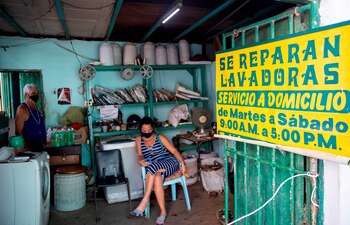 Dos personas son vistas en el interior de un taller de lavadoras hoy, en La Habana (Cuba). EFE/Yander Zamora