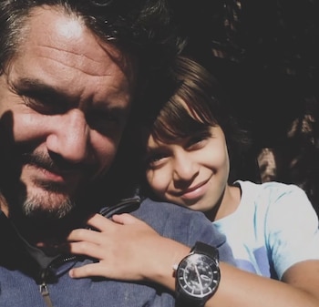 Un hombre con barba sonríe junto a un niño que apoya la cabeza sobre su hombro