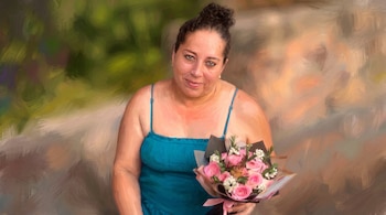 Mujer de mediana edad con cabello oscuro recogido, vestido azul, pendientes, sostiene un ramo de rosas rosadas y una mariposa.