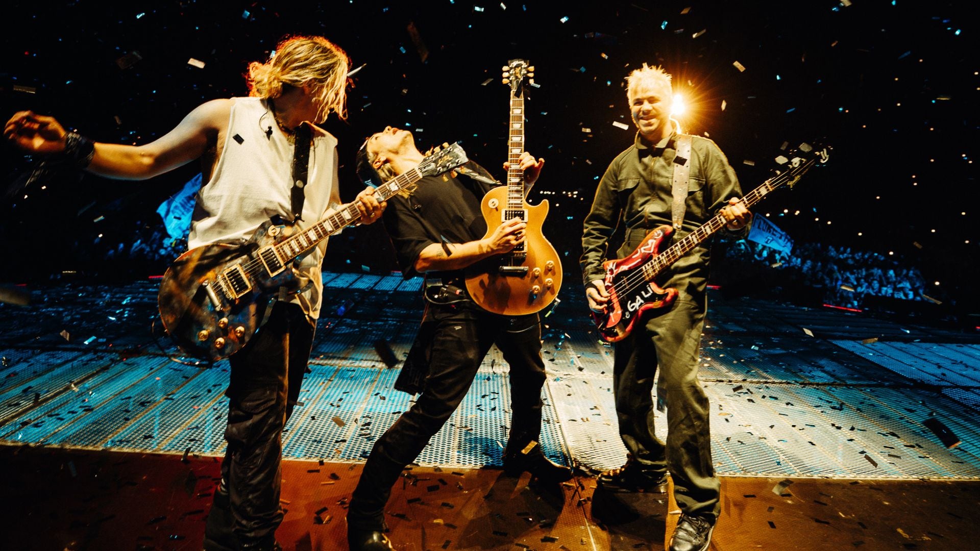 La banda de rock Airbag se presentará en un concierto en el Estadio San Marcos de Lima, Perú, con confetti cayendo sobre el escenario y el público al fondo.