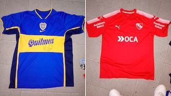 Una camiseta de fútbol de Boca Juniors azul y amarilla con la marca Quilmes y una camiseta de Independiente roja con la marca OCA sobre un piso de baldosas