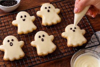 Galletas de mantequilla con forma de fantasma, cubiertas con chocolate blanco y decoradas con ojos negros - VisualesIA