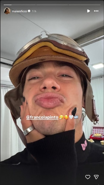 Primer plano de Franco Colapinto con un casco de aviador vintage, haciendo puchero, mientras una mano con uñas negras toca su mejilla