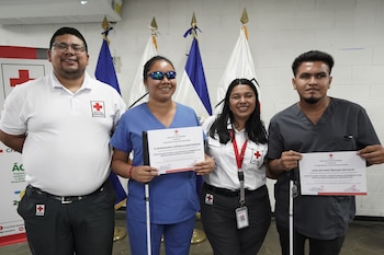 Personas con discapacidad visual muestran los diplomas obtenidos al finalizar el curso de Masoterapia Intermedio impartido por la Cruz Roja Salvadoreña.