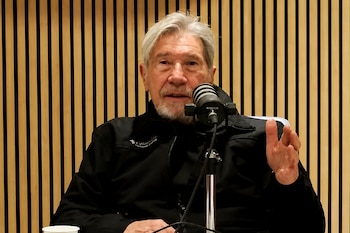 Germán Kraus habla con la mano levantada frente a un micrófono sobre un fondo de madera.