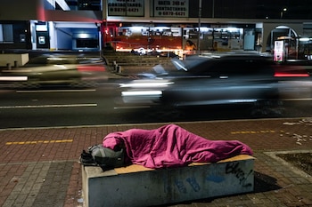 Una persona duerme en un banco de concreto junto a una calle en la Ciudad de Panamá. (Foto AP/Matías Delacroix)
