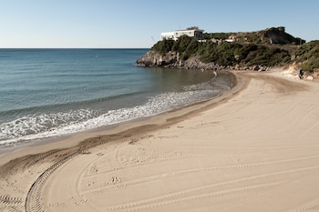 Se aprecia la arena y el mar, al fondo se ve el extremo del "cabo" en el que hay una pequeña elevación de terreno llena de arbustos con una casa encima. (Flickr/Luis Pérez)