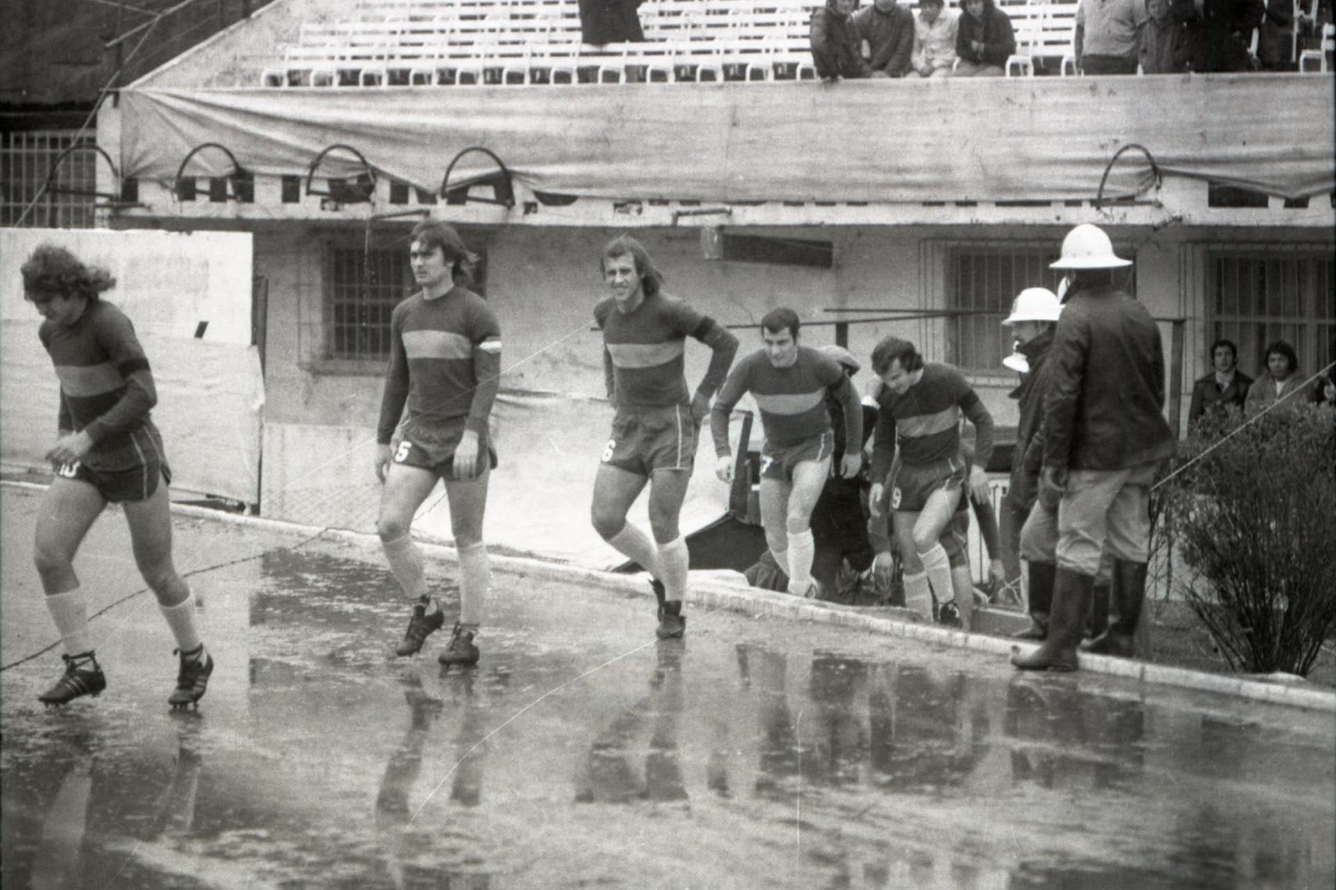 En medio de la lluvia y el viento, Boca sale a la cancha para disputar el partido decisivo ante Huracán: Jorge Riboliz, Rubén Suñé, Roberto Mouzo, Ernesto Mastrángelo y Carlos Veglio encabezan la fila