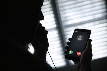 Silueta de una persona con un auricular, sosteniendo un smartphone que muestra una llamada entrante con un ícono de perfil genérico y opciones de aceptar/rechazar.