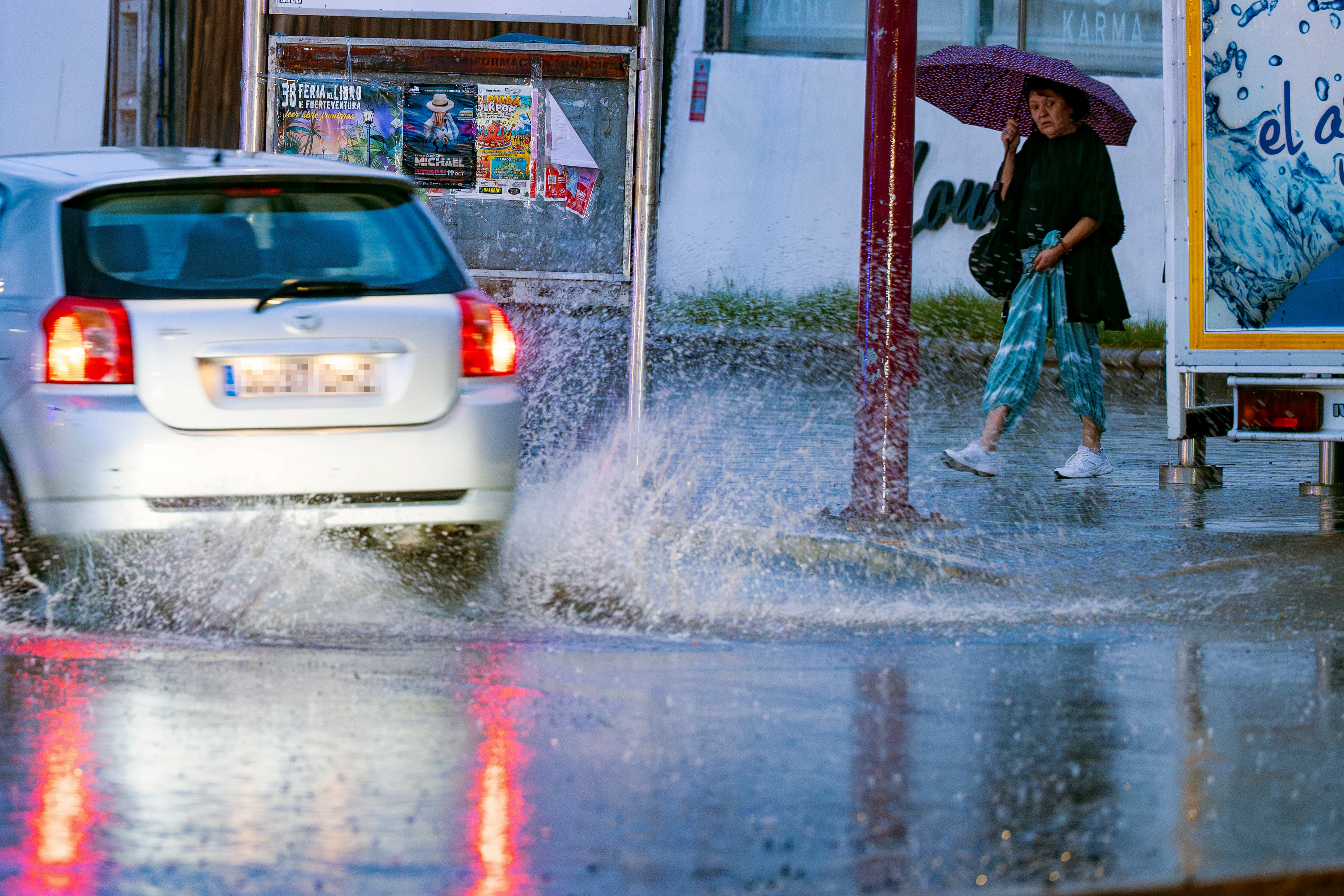 Una mujer se protege este miércoles de la lluvia en Puerto del Rosario, Fuerteventura. (Carlos de Saá/EFE)