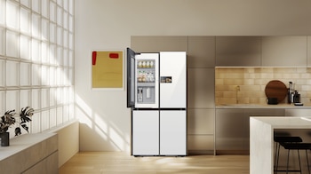 Cocina con un refrigerador blanco de cuatro puertas, una pared de bloques de vidrio, muebles de cocina, una planta y un cuadro abstracto