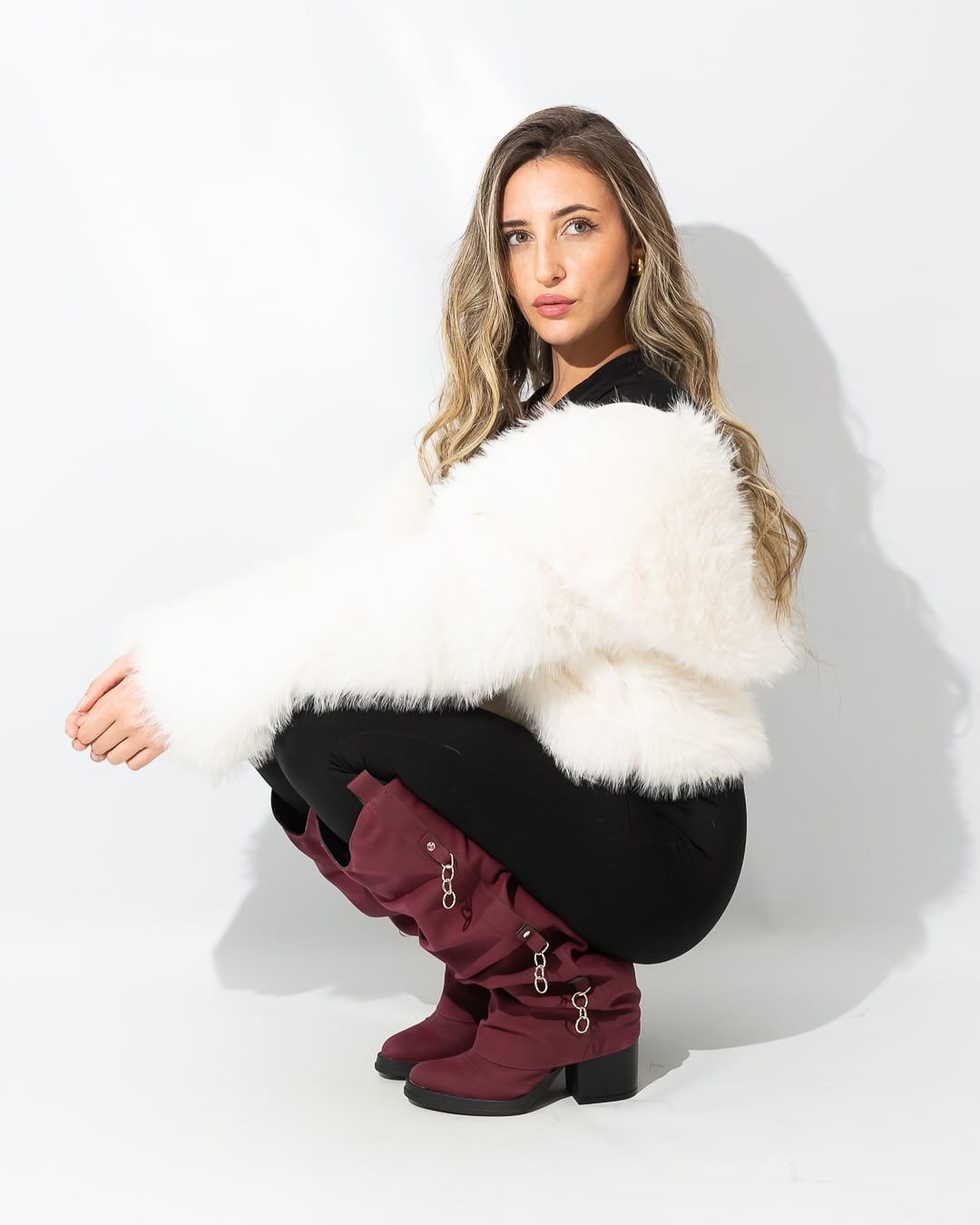 Elige una chaqueta cropped de piel sintética blanca y botas burdeos, logrando un estilismo de invierno contemporáneo y chic (Instagram: @abruduhalde)