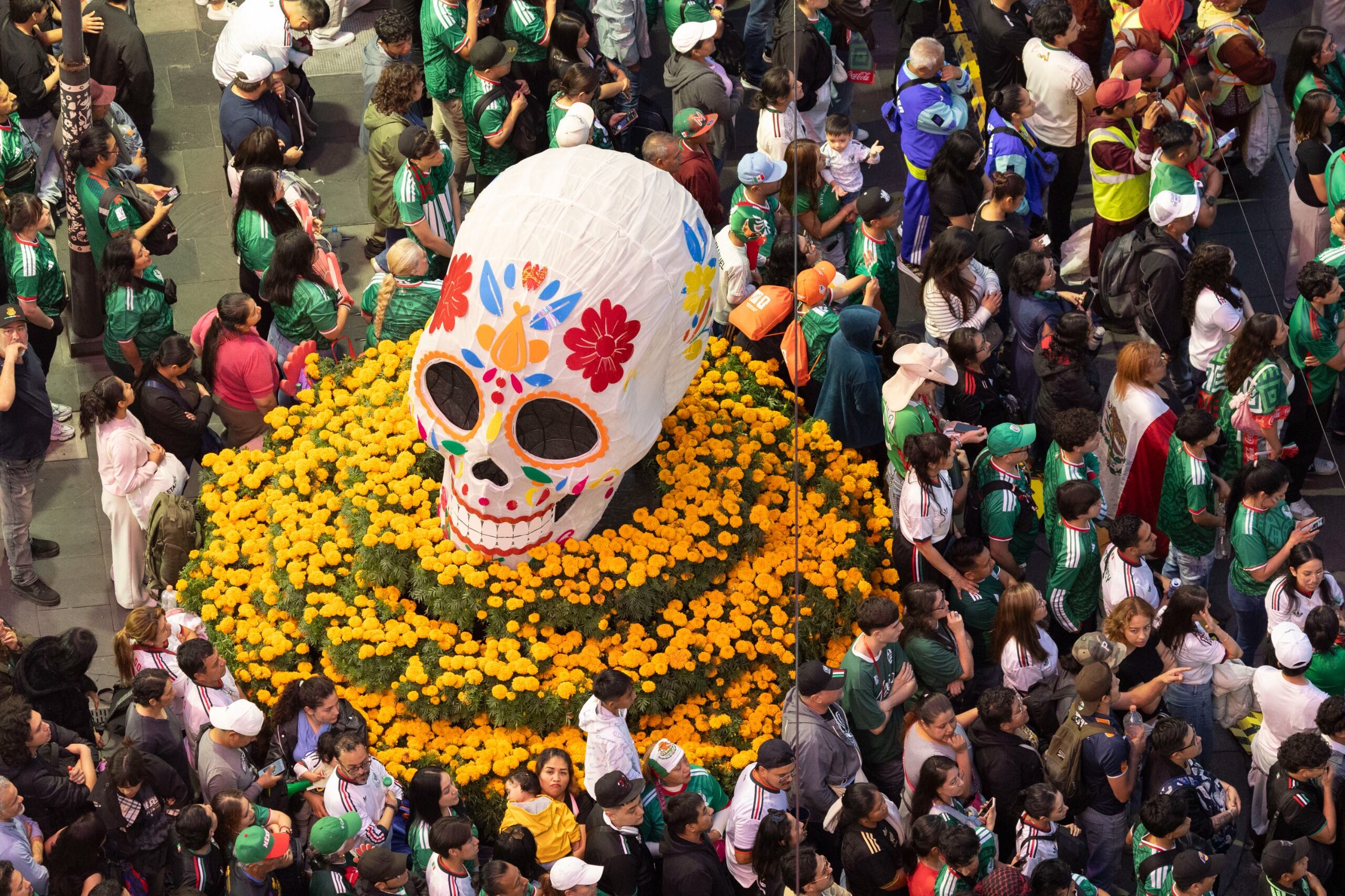 Una multitud de aficionados mexicanos se congrega en el Zócalo CDMX Fan Fest, donde un gran cráneo decorado se erige entre un lecho de flores de cempasúchil. (Jefatura Gobierno CDMX)