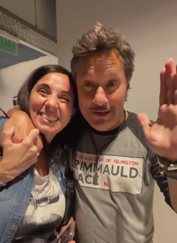 Diego Torres abraza por el cuello a una mujer sonriente y levanta la mano izquierda hacia la cámara
