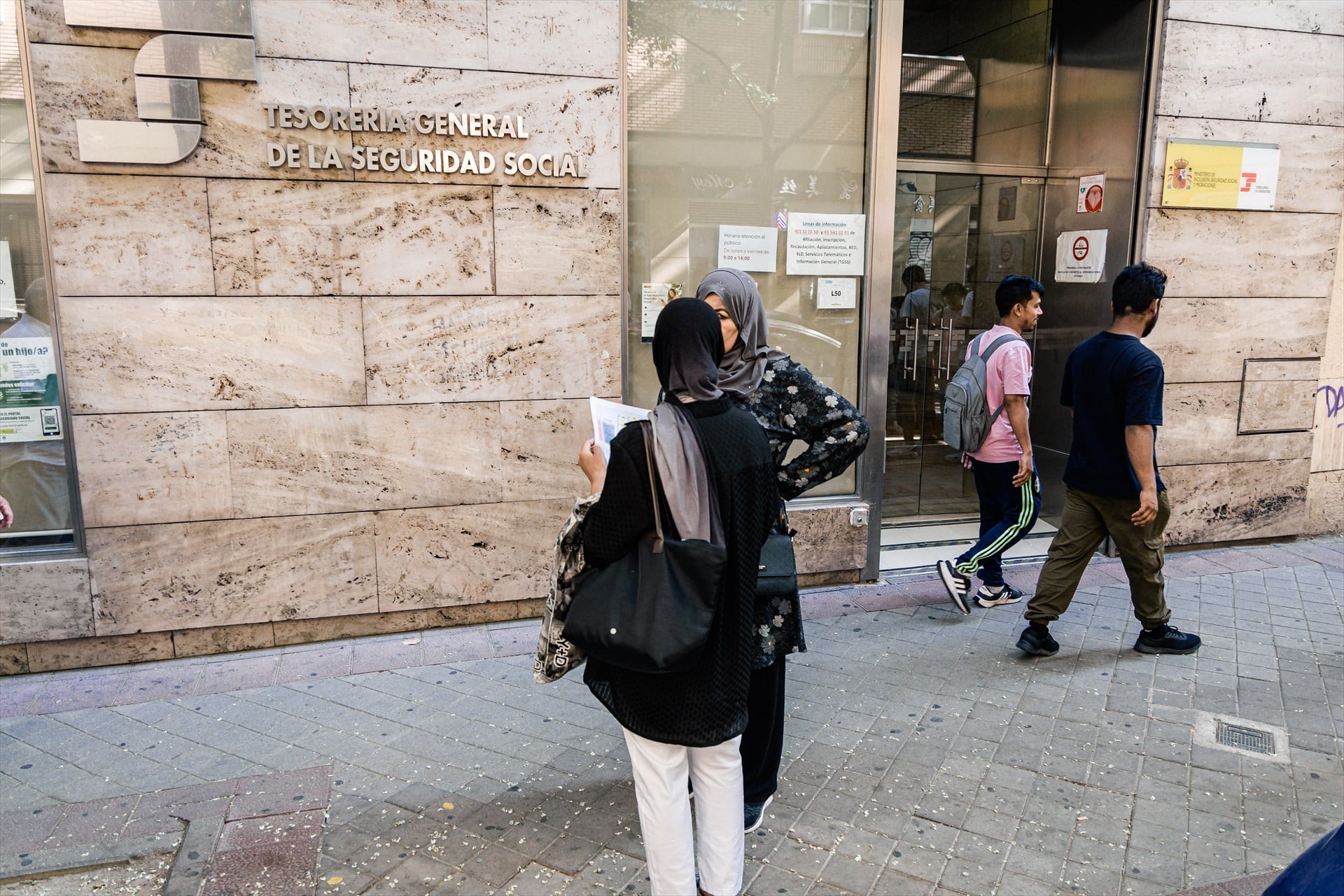 Varias personas migrantes esperan en el exterior de una oficina de la Seguridad Social en Madrid. (Carlos Luján / Europa Press)