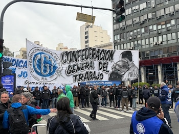 Vista frontal de una manifestación con multitud de personas y una gran pancarta de la Confederación General del Trabajo en una calle urbana. Edificios y semáforo