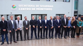 Grupo de aproximadamente diez hombres y dos mujeres de pie frente a un edificio moderno con la inscripción "Secretaría de Seguridad Centro de Monitoreo"