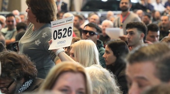 Una mujer rubia levanta una paleta de subasta con el número 0526 y el logo de Santa Fe, rodeada por una multitud de asistentes