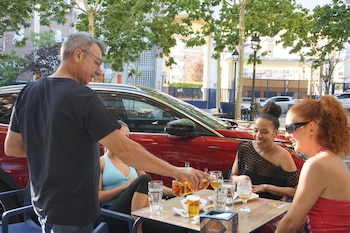 Un camarero sirve una copa en la terraza de un bar a tres jóvenes.