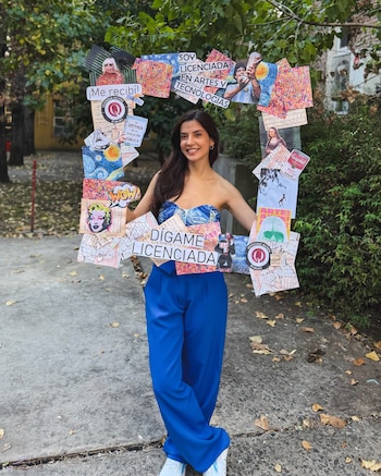 Joven graduada sonriente posa con un marco de celebración creativo, diseñado como un collage de arte y mensajes de su título universitario