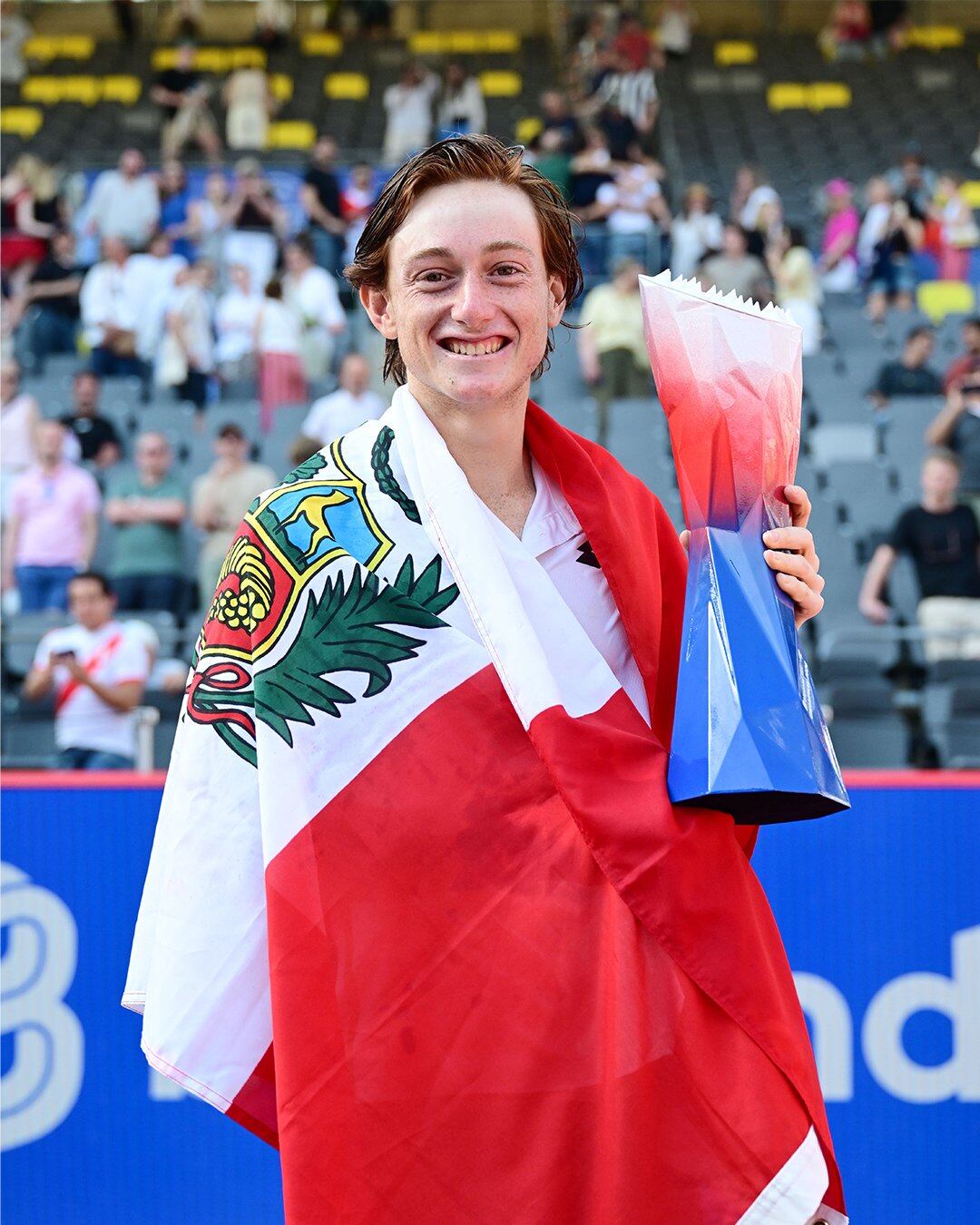 Ignacio Buse celebra su victoria en el ATP 500 Hamburgo, envuelto en la bandera peruana y sosteniendo el trofeo de campeón. (ATP Tour)