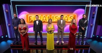 Siete participantes vestidos de gala de pie sobre un escenario frente a un letrero luminoso con la palabra FINALISTAS