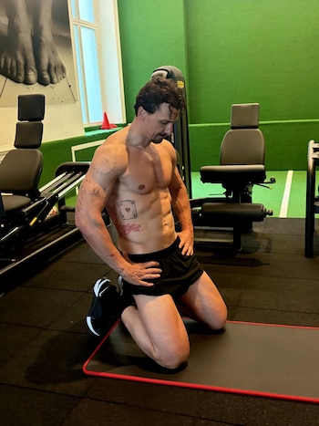 Zlatan Ibrahimović con el torso al descubierto, arrodillado sobre una colchoneta en un gimnasio con aparatos al fondo