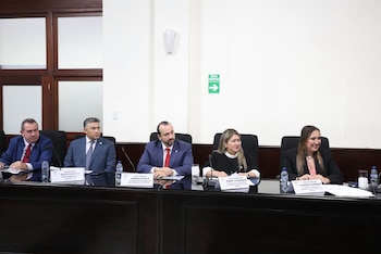 Cinco funcionarios judiciales sentados a una mesa de conferencia con letreros identificatorios frente a cada uno