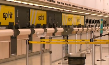 Mostradores de facturación de Spirit Airlines vacíos en la Terminal 4 de Fort Lauderdale. Carteles amarillos de "spirit" y cintas de barrera con el logo restringen el paso