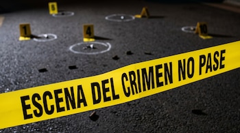 Cinta amarilla 'Escena del Crimen No Pase' en diagonal. Marcadores de evidencia numerados y círculos blancos delinean casquillos sobre asfalto oscuro.