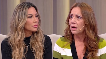 Dos mujeres sentadas, una de cabello rubio con blusa negra y la otra de cabello rojizo con suéter a rayas, llevan micrófonos.