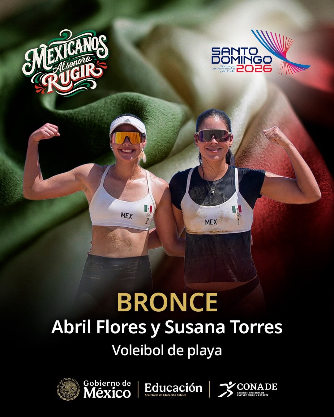Abril Flores y Susana Torres posan con la bandera mexicana de fondo tras obtener la medalla de bronce en voleibol de playa en los Juegos Centroamericanos y del Caribe Santo Domingo 2026. (X / CONADE )